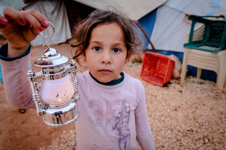 A Young Girl Holding A Silver Lantern