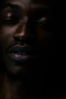 A dramatic close-up shot of a man with closed eyes, creating a serene and moody ambiance.