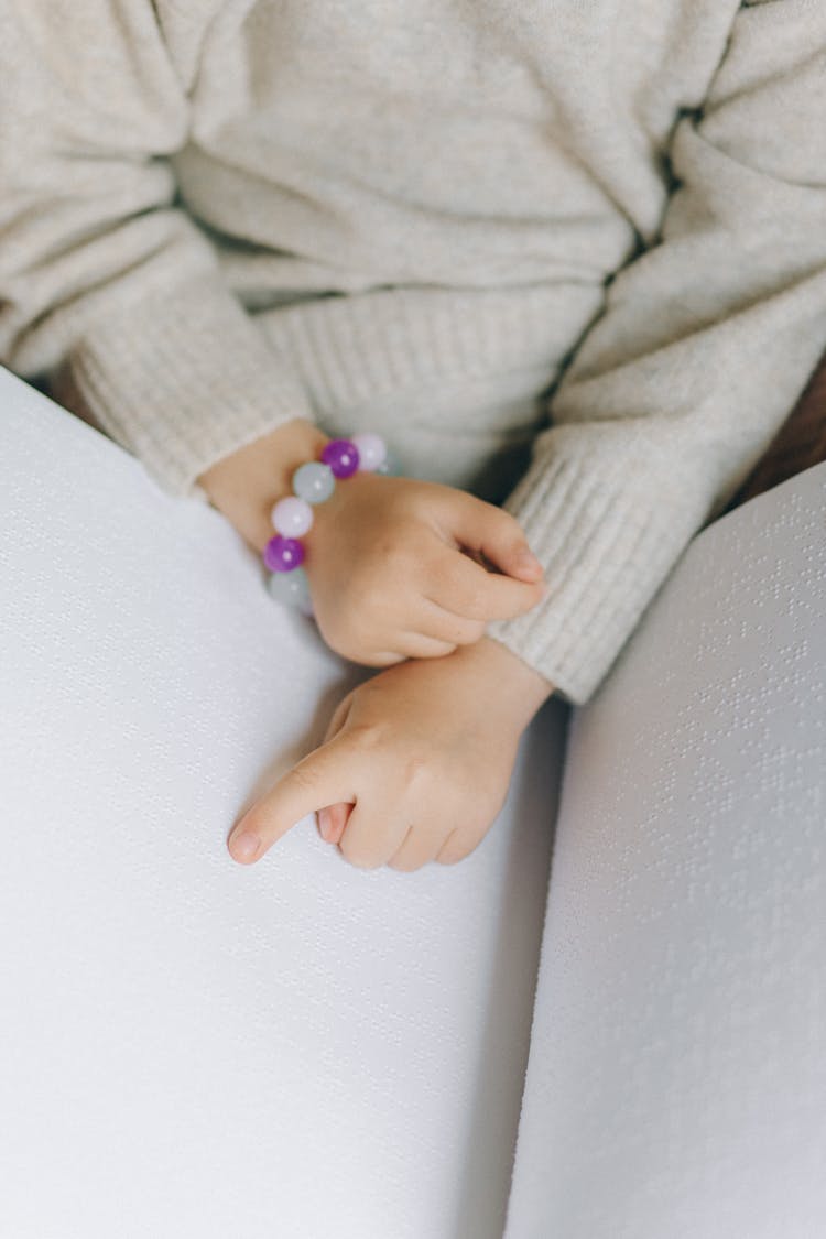 A Child Touching A Braille Book