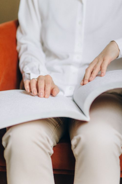 Free Close-up of hands reading a braille book, symbolizing literacy for the visually impaired. Stock Photo
