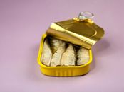 Canned fish in package on lilac background