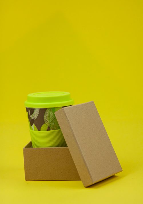 Free Isolated eco friendly box with lid containing disposable green cup on yellow background Stock Photo