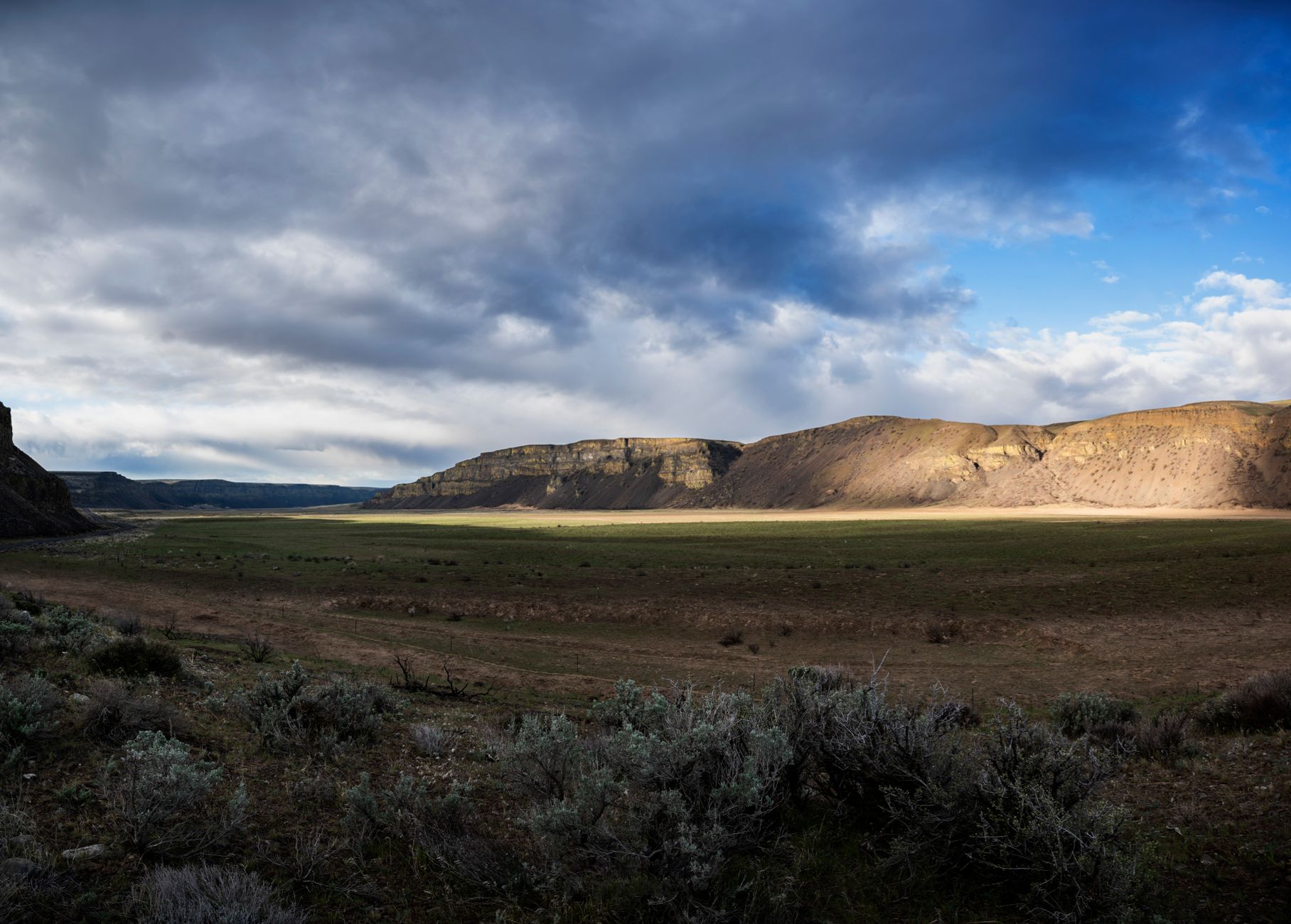 Breathtaking view of Moses Coulee's expansive grasslands under a dramatic cloudy sky.