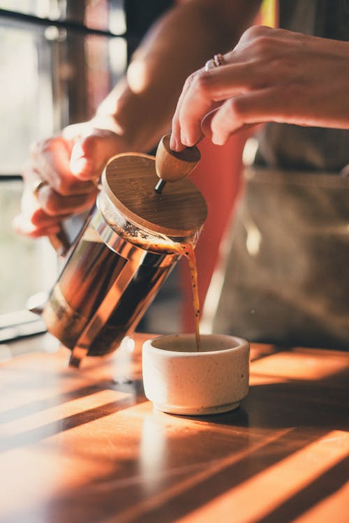 Photo of Person Pouring Brewed Coffee on Ceramic Mug