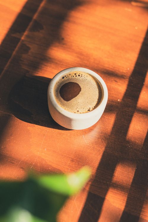 Free Top view of aromatic espresso on a wooden table, with warm sunlight filtering through. Stock Photo