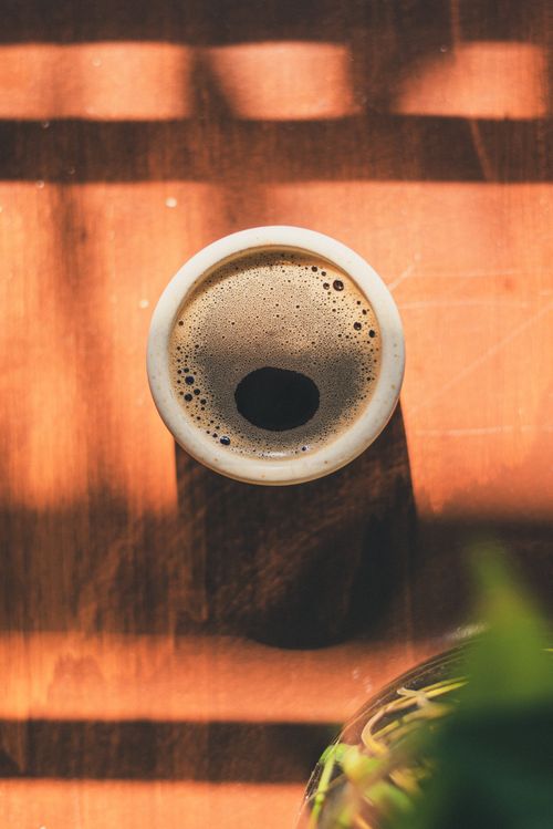 Free A warm cup of aromatic coffee captured from above on a sunlit wooden table, highlighting cozy morning vibes. Stock Photo
