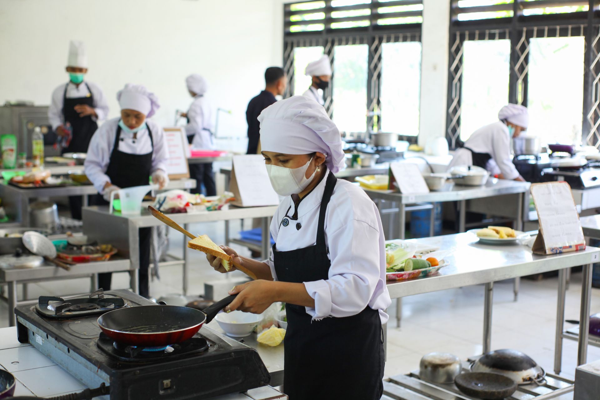 Chefs practicing culinary skills in a training kitchen setting