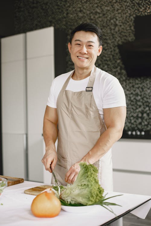 A Man in White Shirt and Apron Smiling in the Kitchen