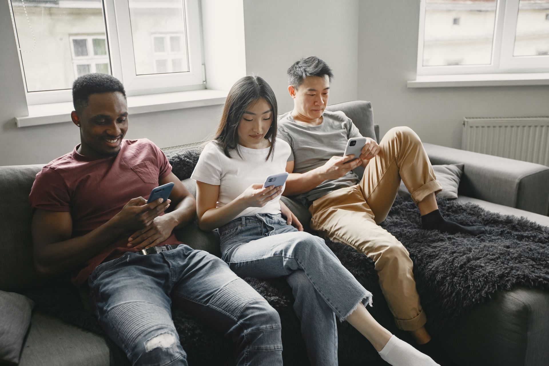 A group of diverse friends lounging on a sofa, each using a smartphone.