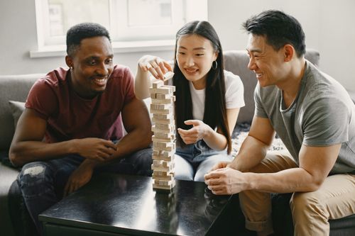 Free Friends enjoying a game of Jenga indoors, focusing on teamwork and fun. Stock Photo