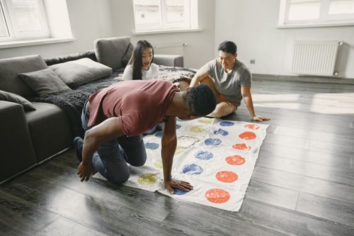 Free Three friends enjoy a fun game of Twister in a cozy living room setting. Stock Photo