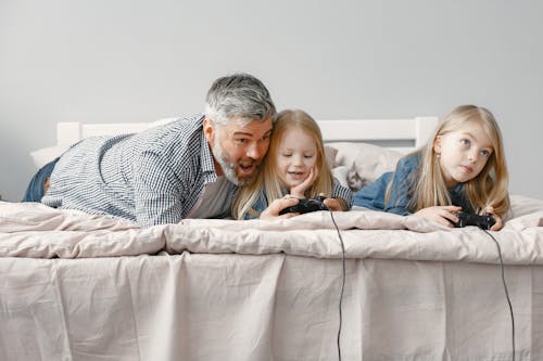 Free Father and His Children Playing on the Bed Stock Photo