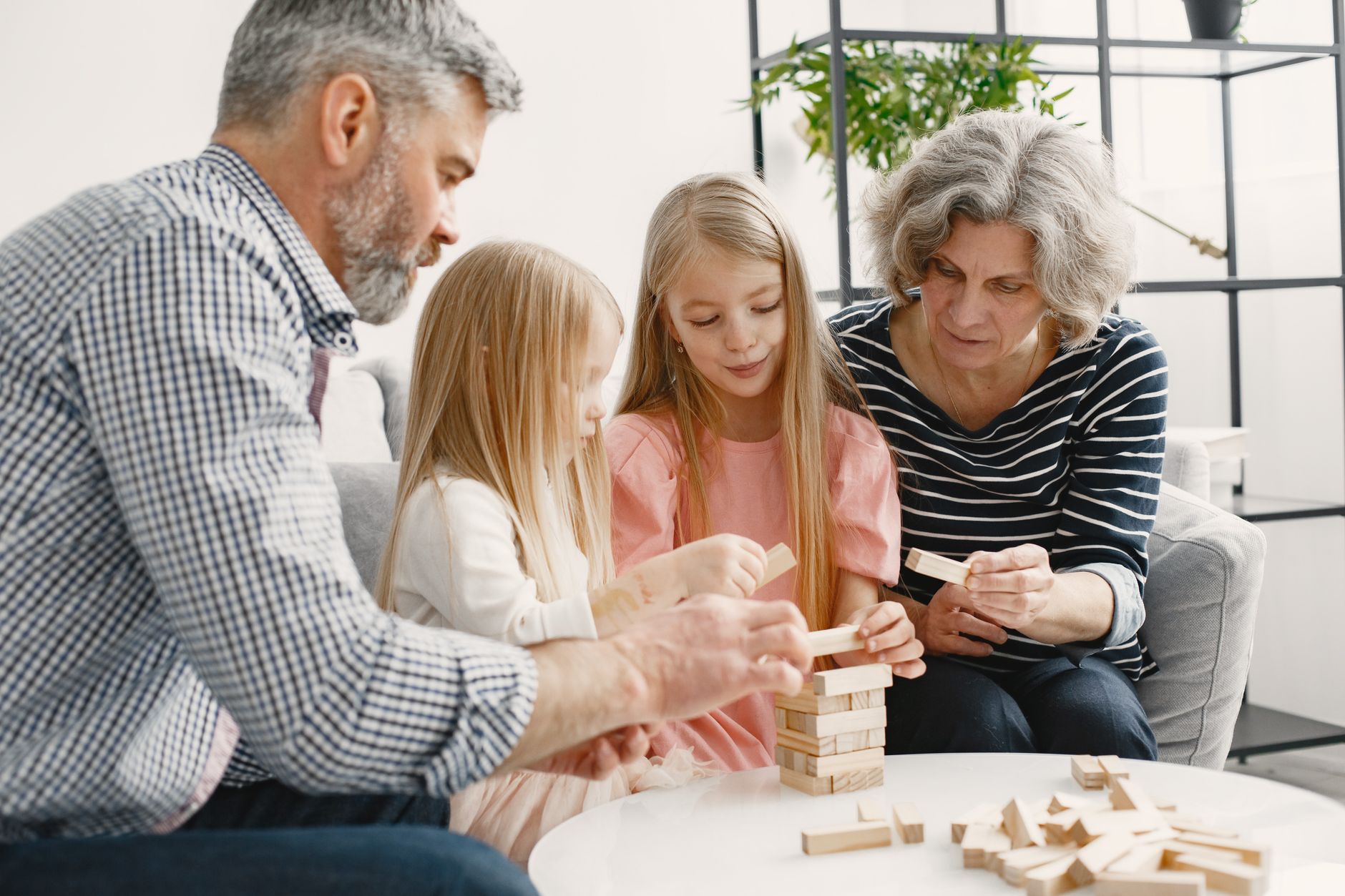 A family enjoying time together playing a block stacking game in their living room.