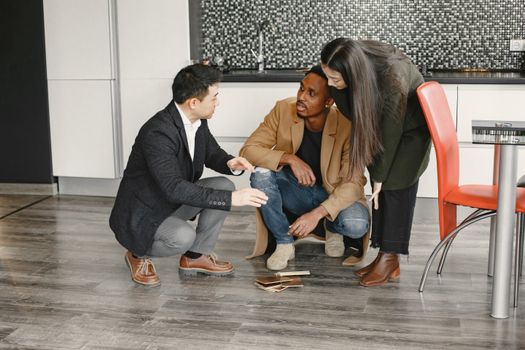 A diverse group of adults gathered indoors, discussing interior design options with flooring samples.