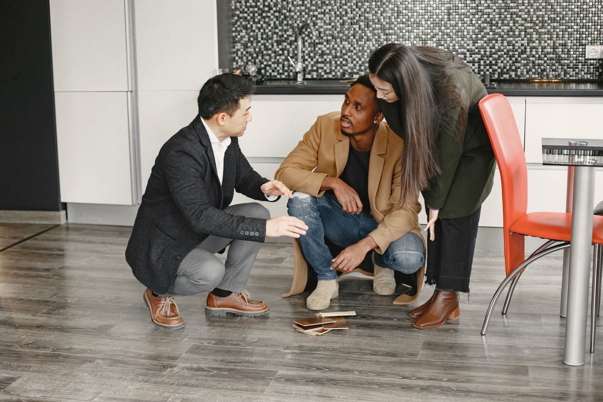A diverse group of adults gathered indoors, discussing interior design options with flooring samples.