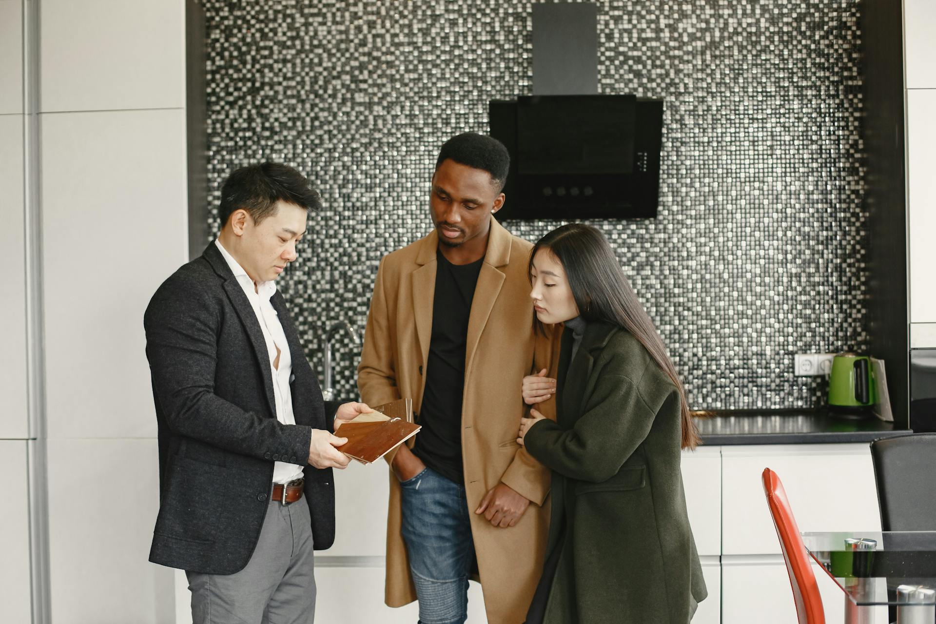 A business meeting in a contemporary kitchen showing diverse professionals discussing strategic options.