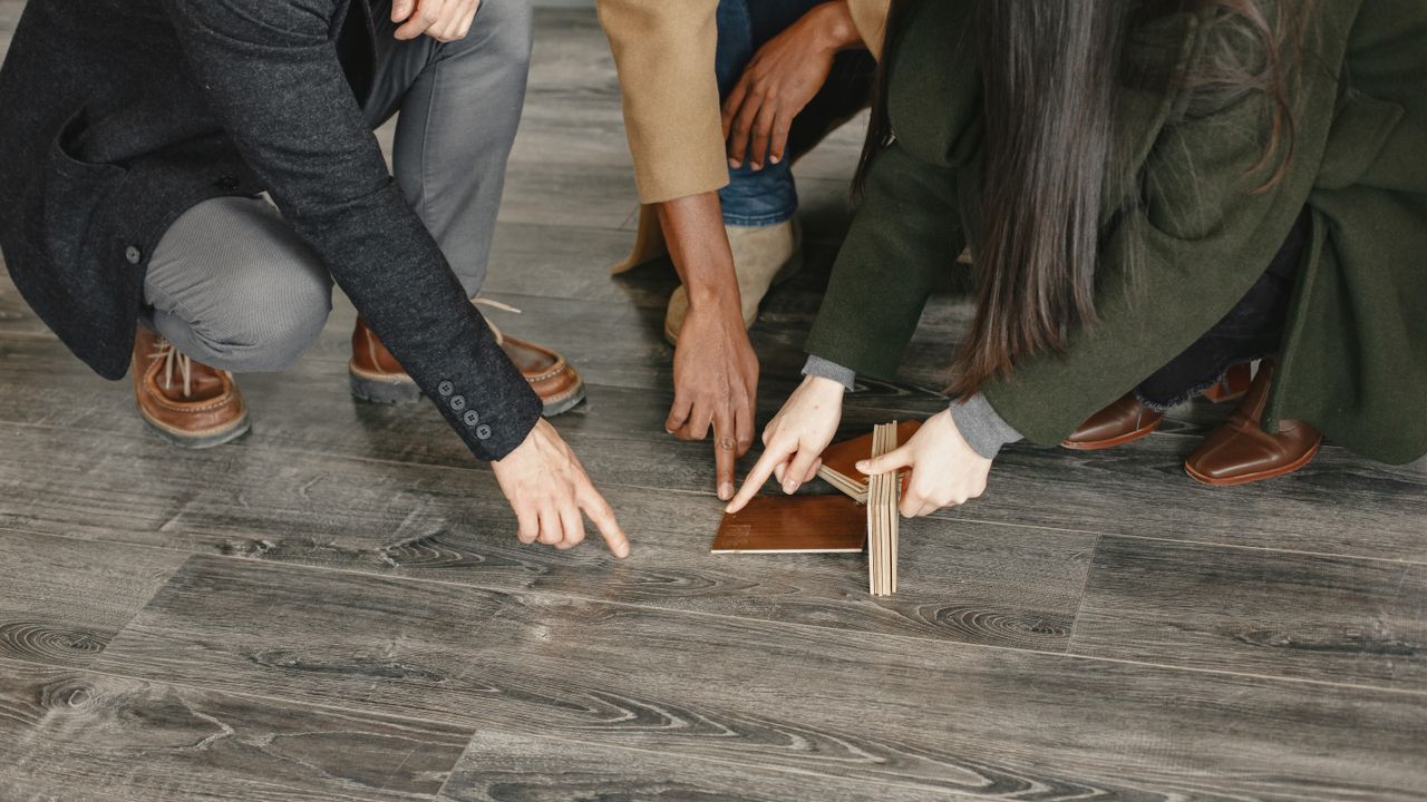 Three people choosing a floor, looking at wood-effect flooring samples laid out on the floor