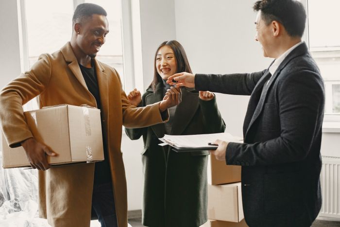 A diverse couple joyfully receives keys to their new home from a real estate agent