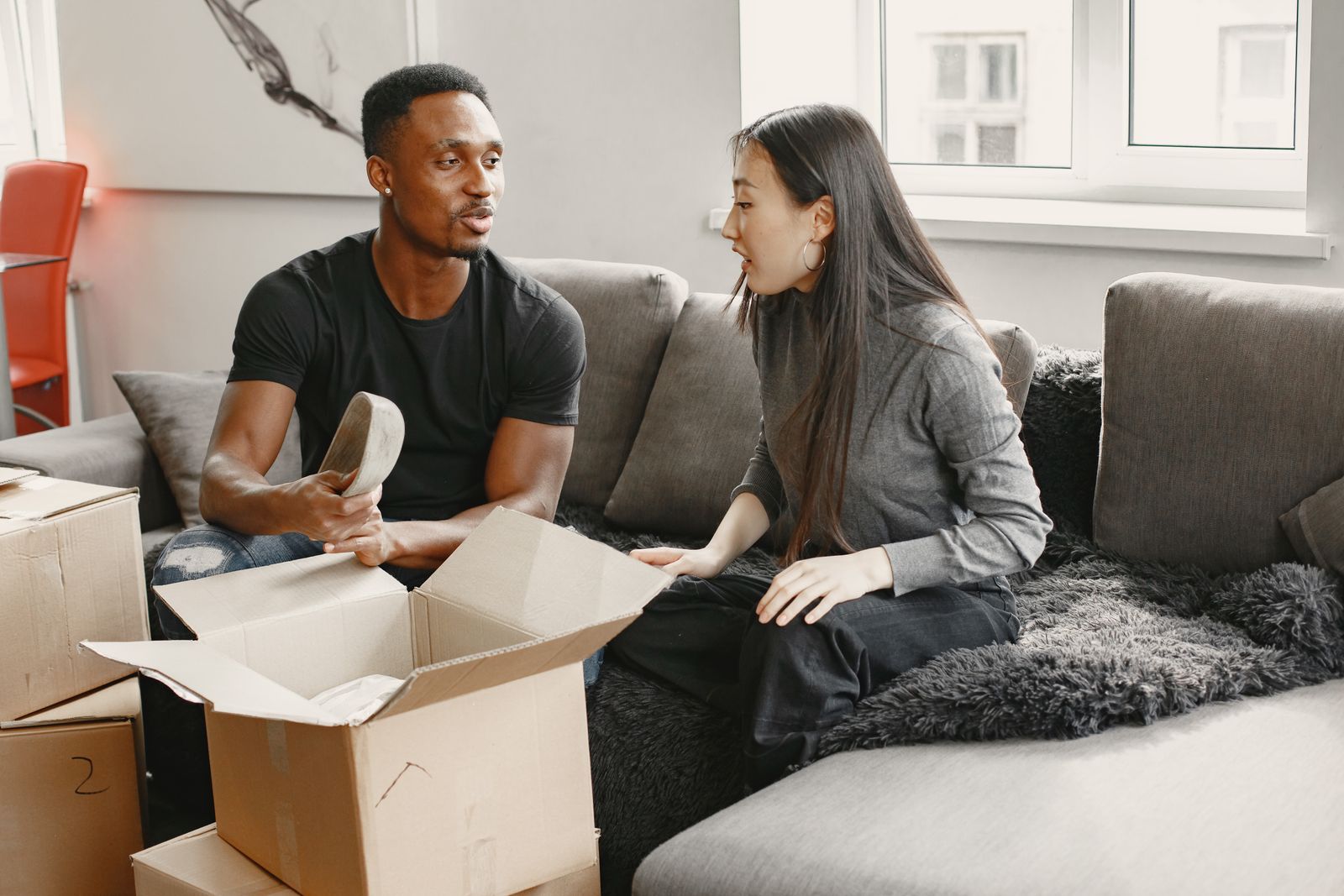 A couple talking on a sofa beside moving boxes