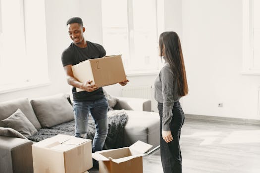 Happy couple carrying boxes into their new home, symbolizing a fresh start indoors with lots of natural light.