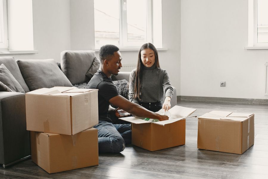 A couple unpacking moving boxes in the living room of their new home