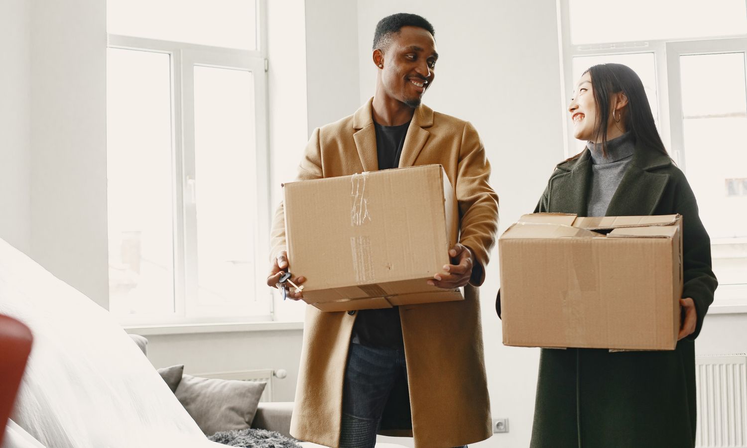 Pareja sujetando cajas de mudanza en el interior de una vivienda