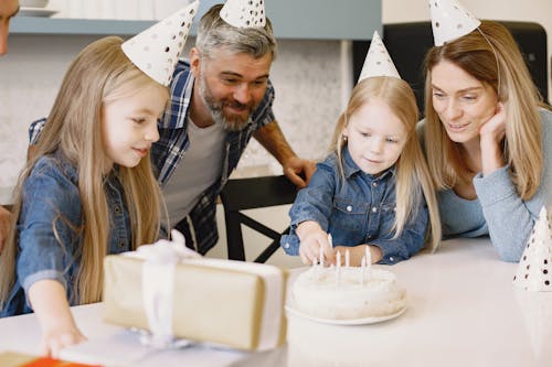A Happy Family Wearing Party Hats while Looking at the Cake