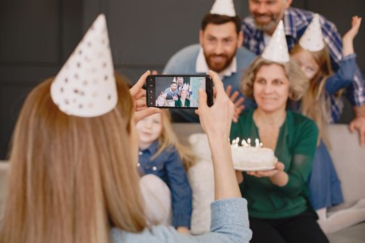Family gathering celebrating with cake, party hats, and smiles, captured in a cozy setting.