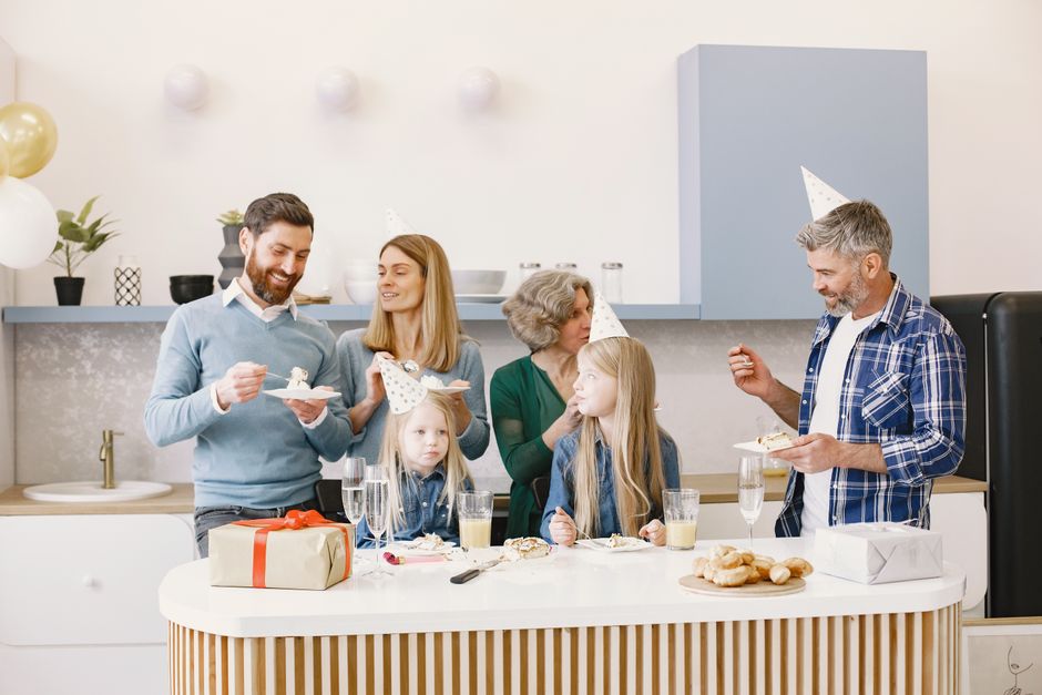 personalized gifts for grandparents - Happy family enjoying a celebration with cake and gifts in a cozy kitchen setting.
