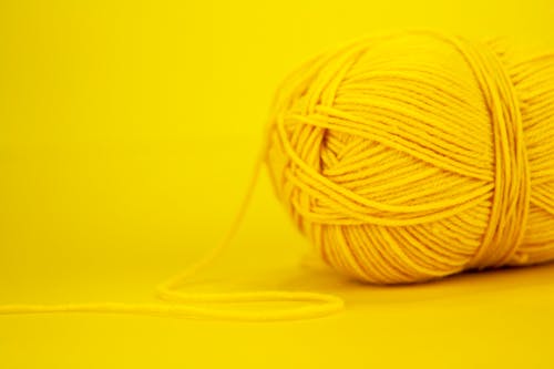 Fragment of woolen yarn for knitting of yellow color placed on bright background