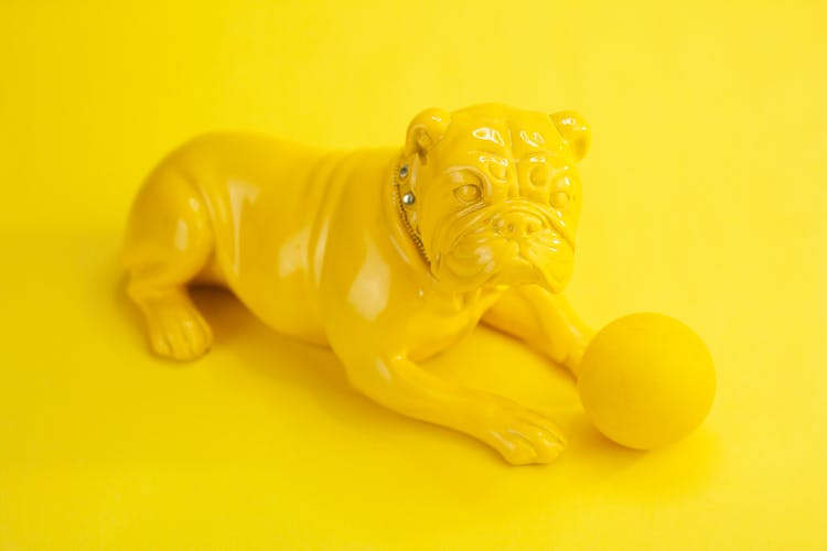 Yellow Figurine Of Dog With Ball