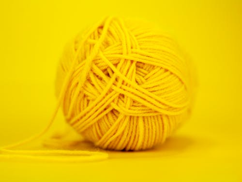 Regular ball of colorful yellow yarn placed on bright monochrome background in soft focus