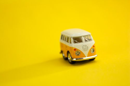 Free Small retro white and yellow toy van placed on centre of bright yellow background in studio Stock Photo