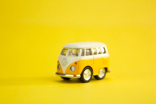 Vintage yellow and white miniature of retro van placed against bright yellow background
