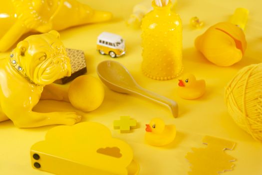 Composition of various yellow decorations and toys spread out on bright yellow table in studio