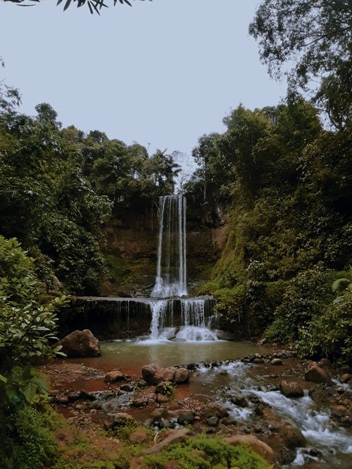 Free A stunning waterfall cascades through a lush forest, surrounded by vibrant greenery and rocky terrain. Stock Photo