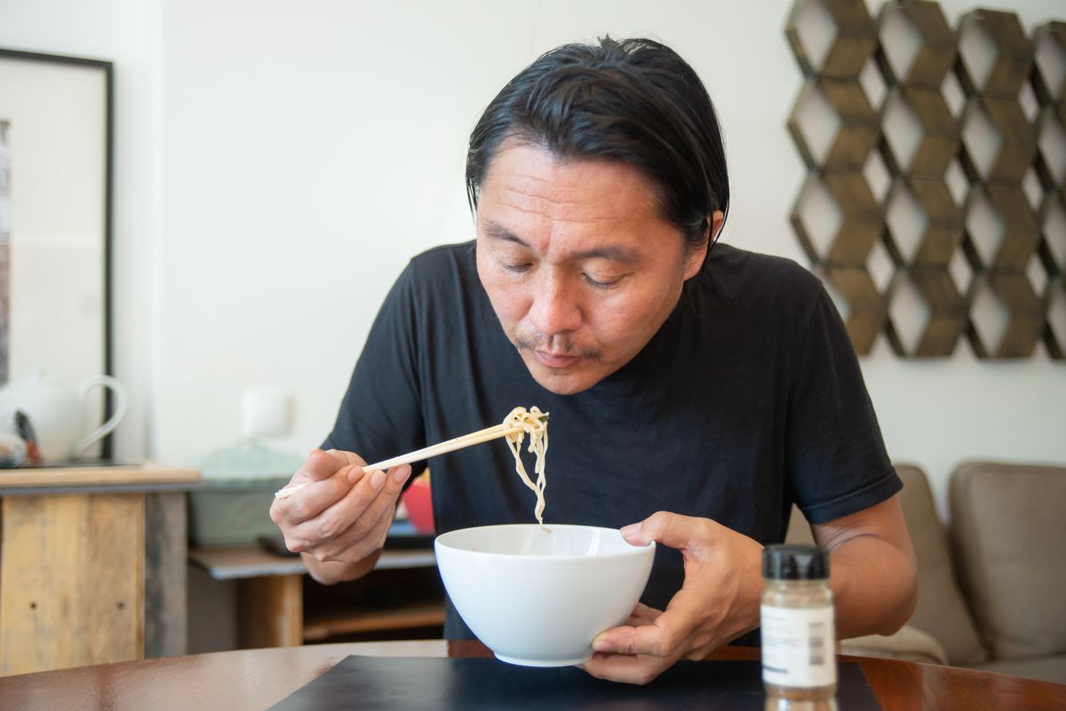 Man eating a bowl of noodles with chopsticks