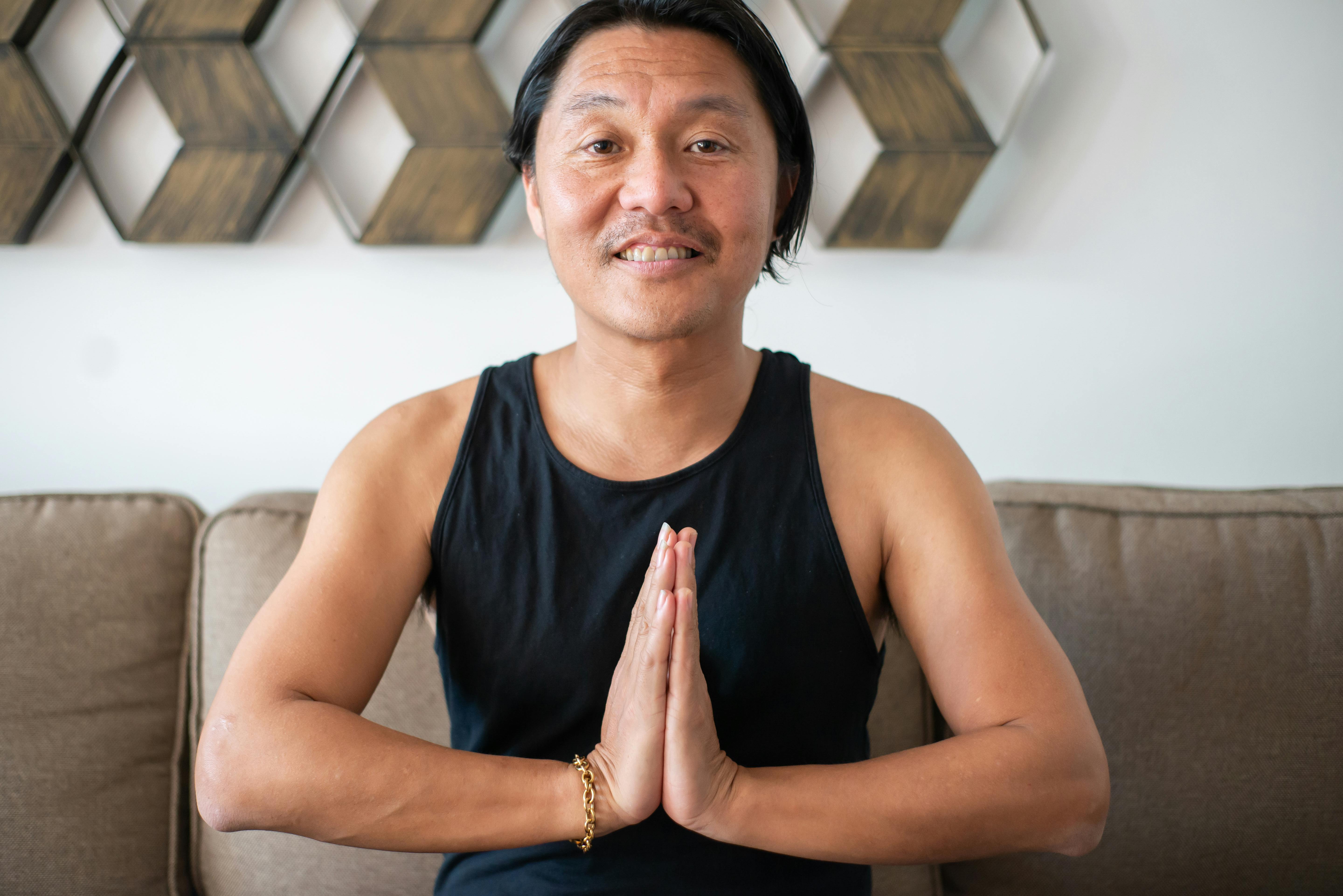 A Man in Black Tank Top Smiling with His Hands Together