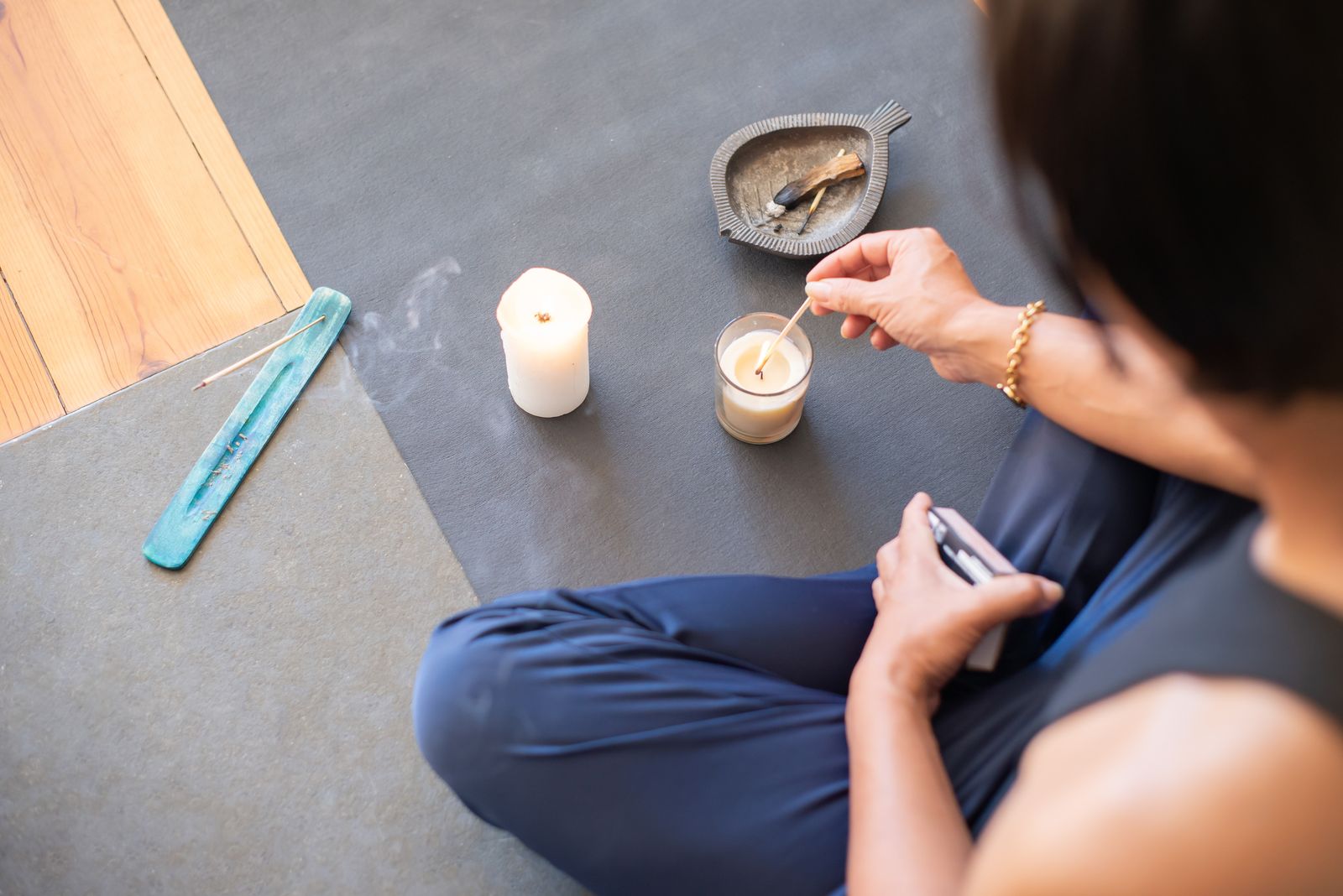 A person practicing trataka meditation by gazing steadily at a candle flame in a dim room