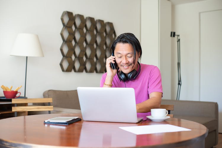 Man Talking On The Phone While Using Laptop