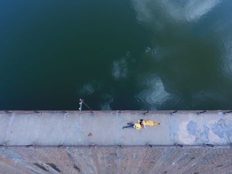 Aerial shot capturing a couple lying on a pier by the calm sea in Junagadh, India.