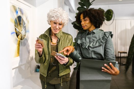 Two diverse women collaborating in a well-lit office space, engaging with technology.