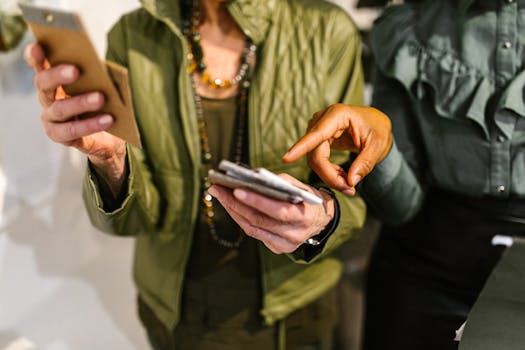 Two businesswomen collaborating using mobile phones in a modern office setting.