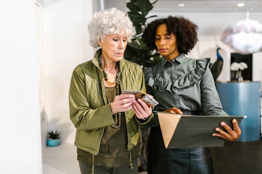 Two professional women discussing work-related documents in a stylish office setting.