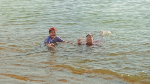 Two Boy on Brown Body of Water