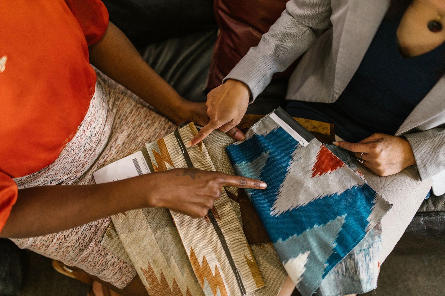 訂製窗簾估價必備資訊:新手清單全攻略 Two professionals assessing colorful fabric swatches for interior design project.