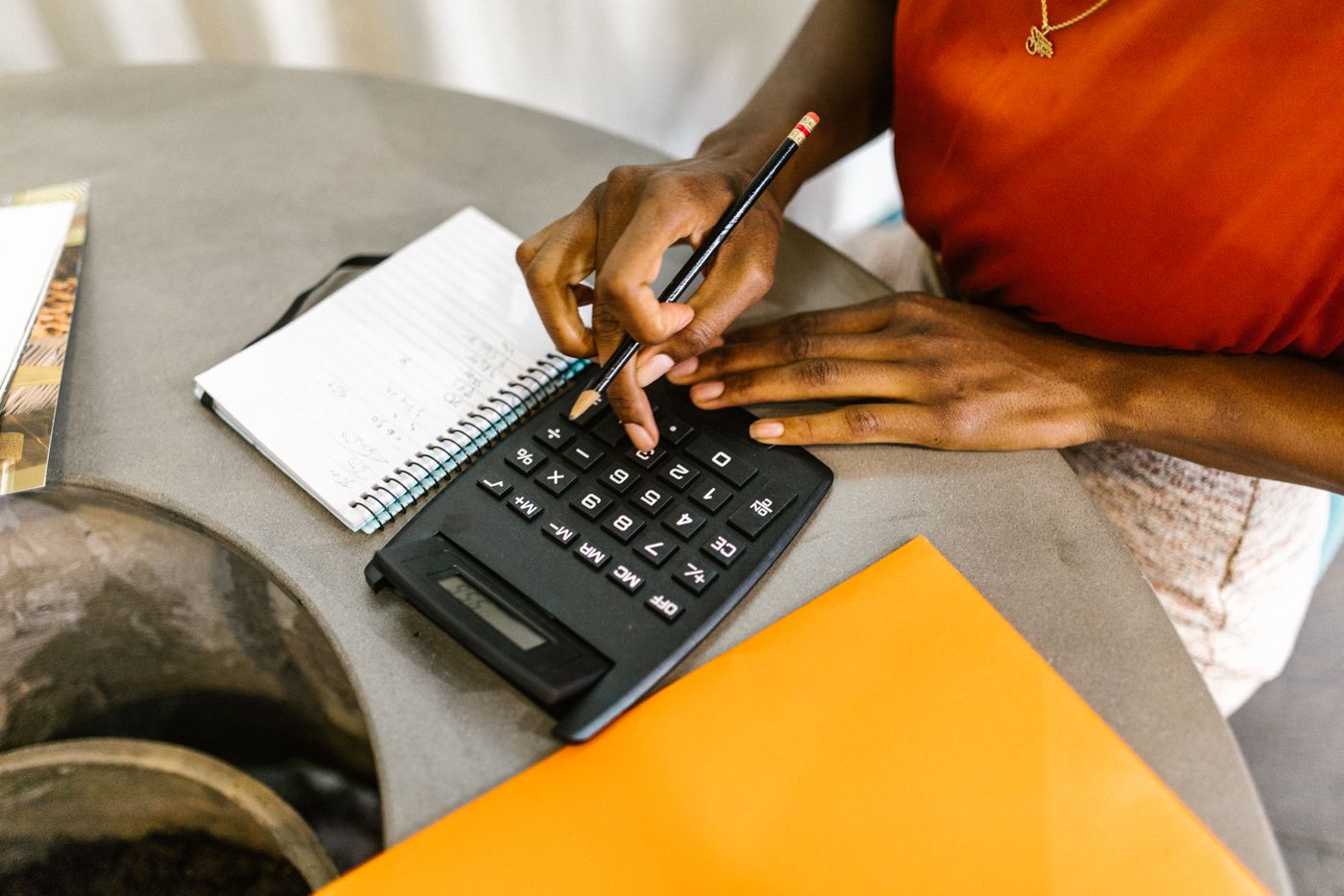 Black woman using a calculator and notebook to plan a short-term loan repayment