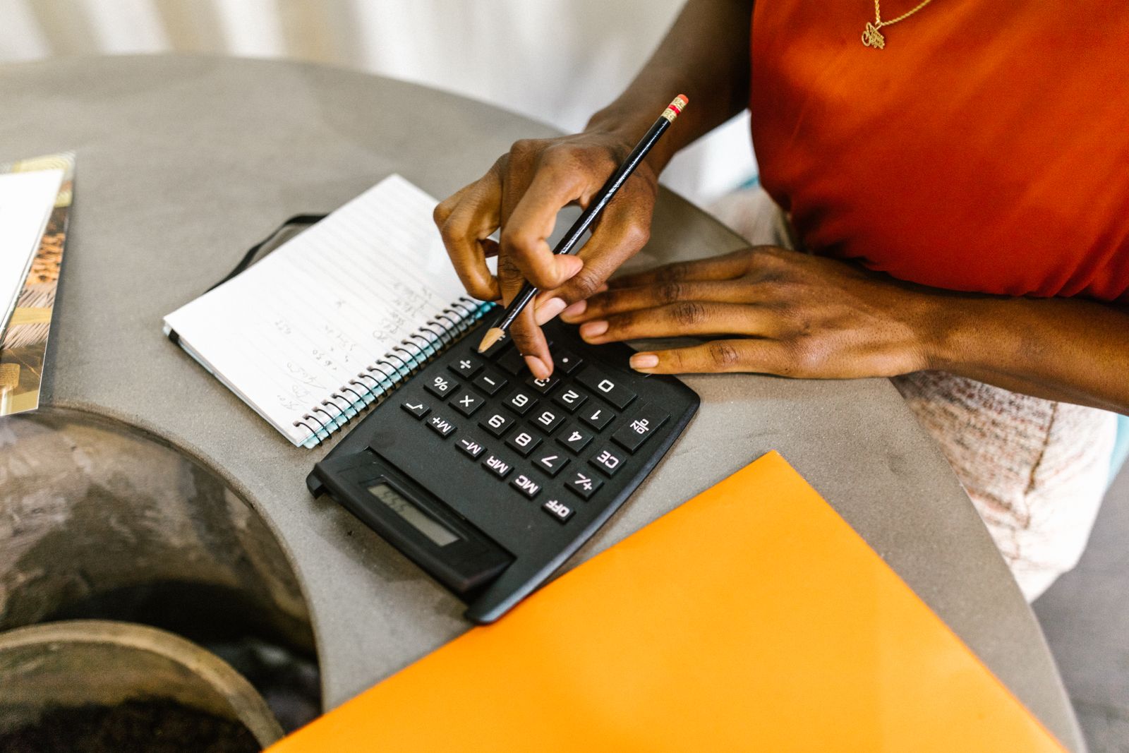 Black woman using a calculator and notebook to plan debt repayments