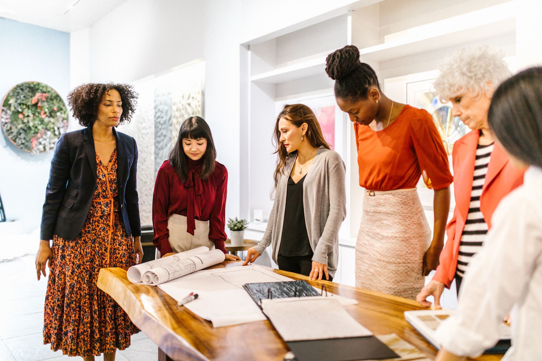 A diverse group of professional women discussing plans in a modern office setting.
