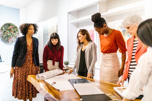 A diverse group of professional women discussing plans in a modern office setting.
